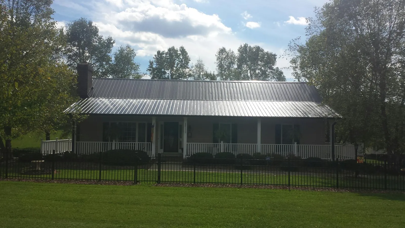 Gray metal roof on a brick ranch with a full width front porch — Gutter Guard Installation work by our crew in Donnelly