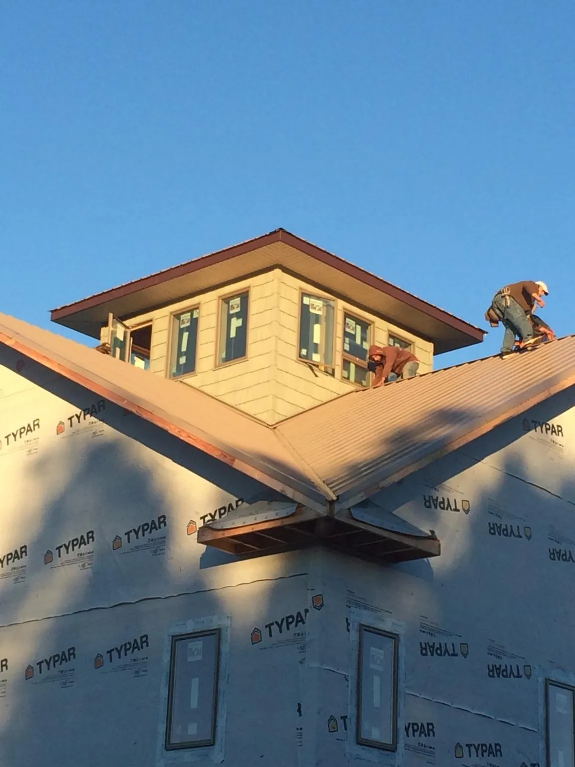 Roofers working around a rooftop cupola on a new metal roof at sunset — Roof Waterproofing in Donnelly by Roofing Brothers